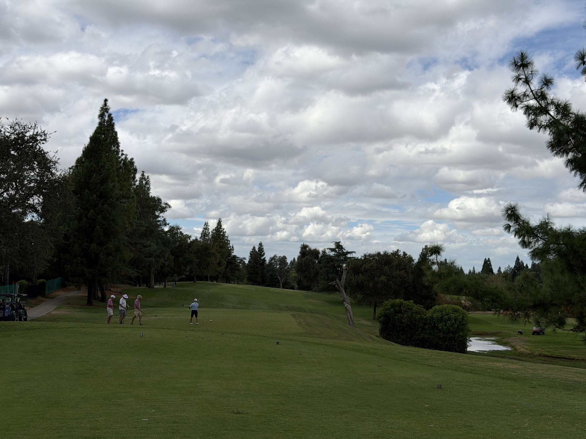 Golfers walking up a Diamond Oaks fairway past the creek