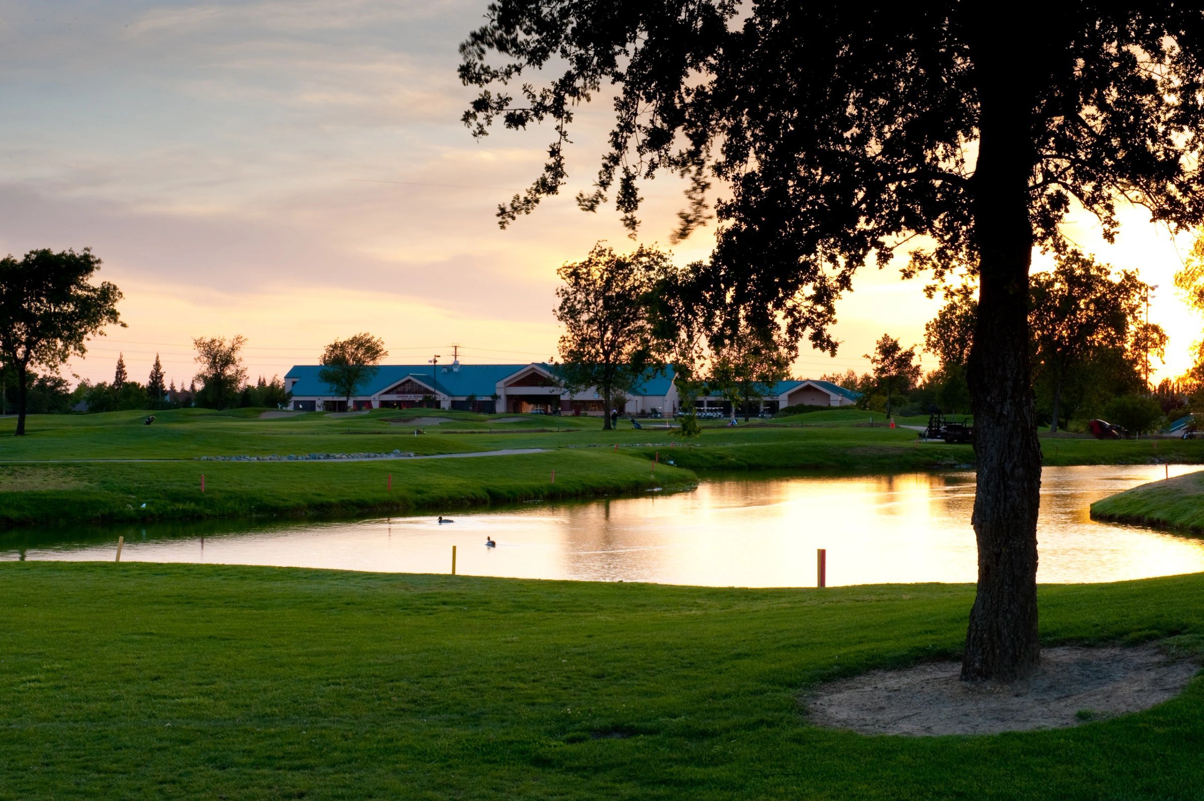 Sunset over the water at Woodcreek Golf Club with the clubhouse reflected in the pond