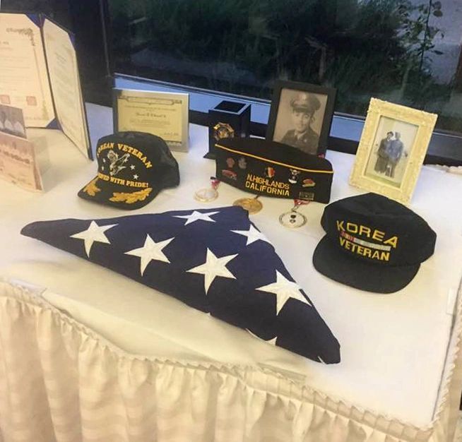 A memorial tribute table with a folded flag and framed photographs