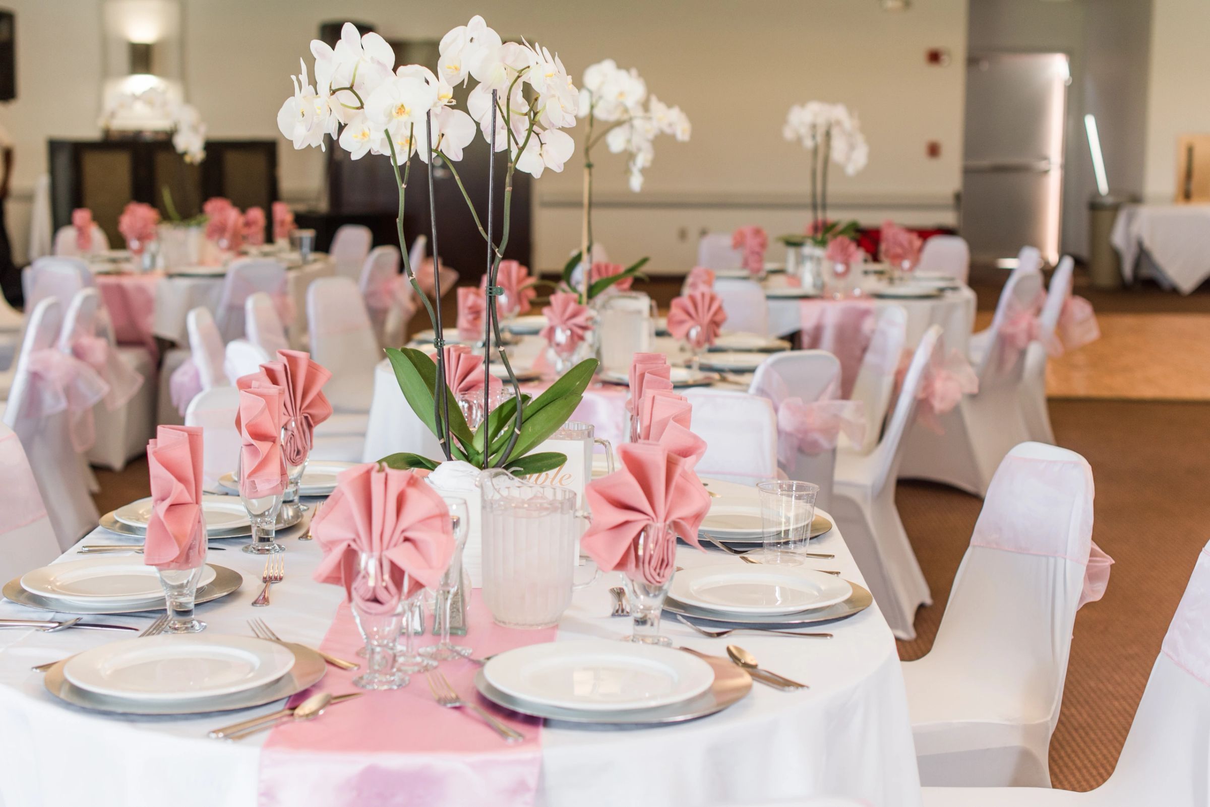 Reception tables set with white orchids and blush napkins