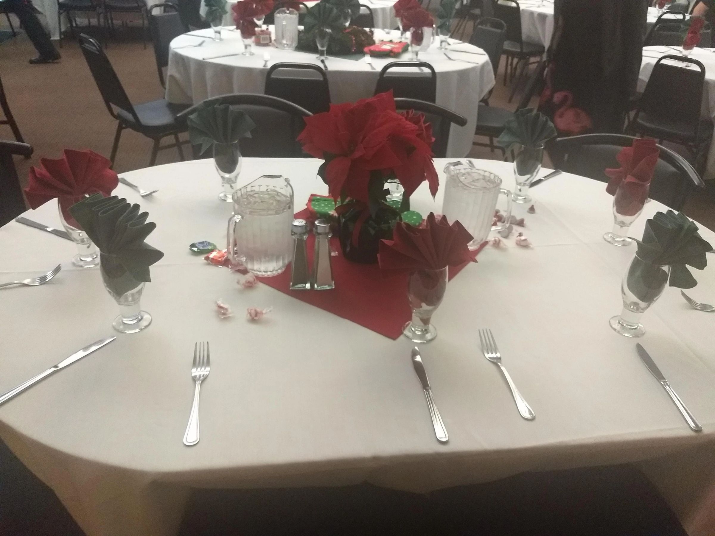 Round table dressed with poinsettias and red napkins for a holiday party
