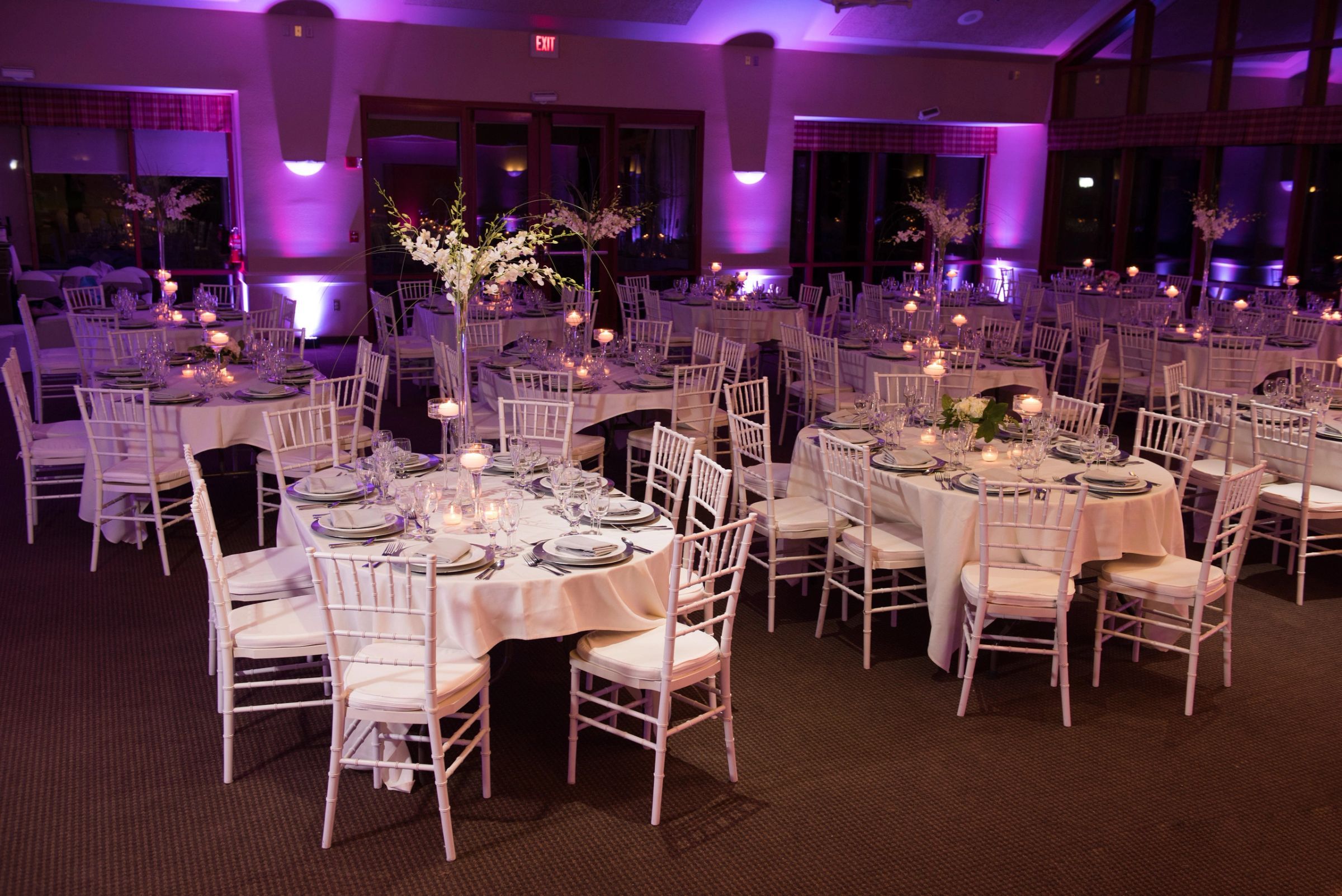 Reception room washed in purple uplighting with candlelit tables